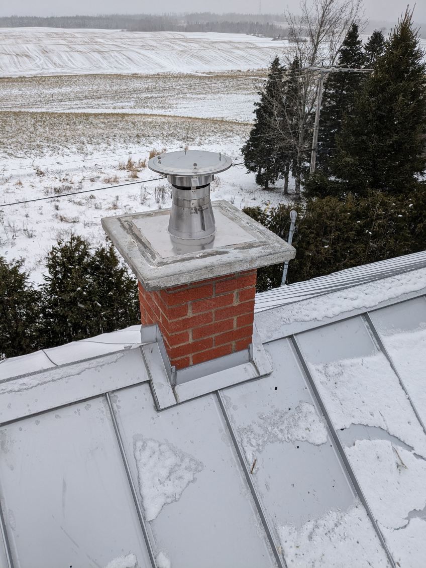 Une cheminée en brique se trouve au sommet d'un toit en métal.
