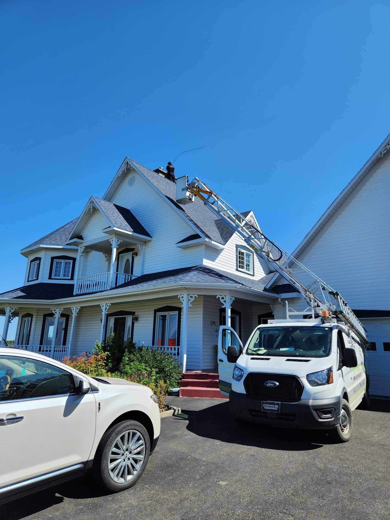 Une camionnette blanche est garée devant une grande maison blanche.