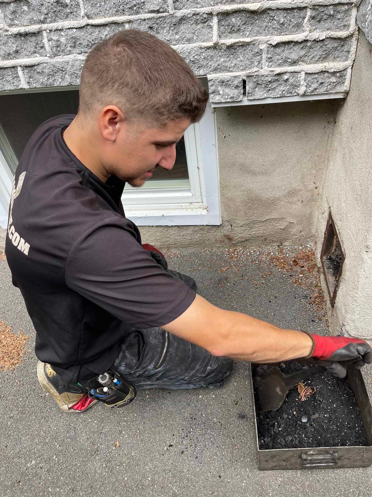 Un homme est agenouillé par terre à côté d'un mur de briques.
