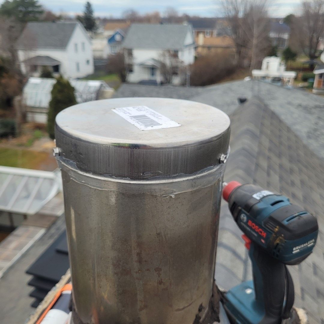 Un cylindre en acier inoxydable est posé sur un toit à côté d'une perceuse Bosch.