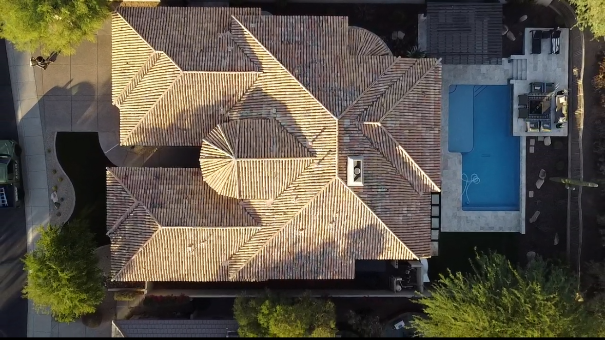 An aerial view of a house with a striped roof and a pool.