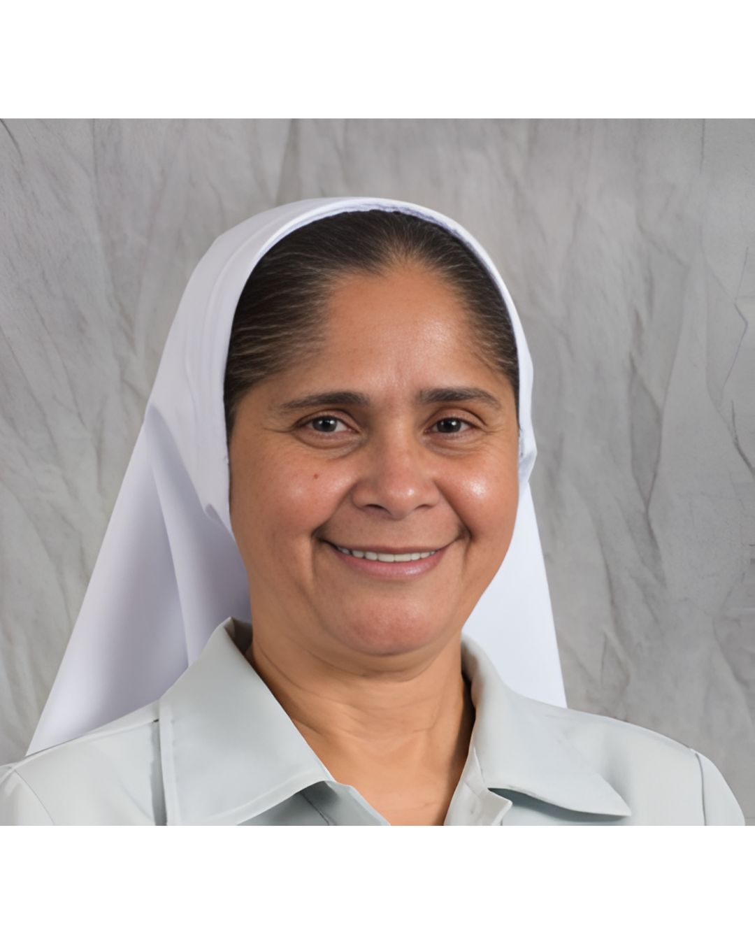 Headshot of a person wearing a white religious habit against a grey background, smiling at the camera.