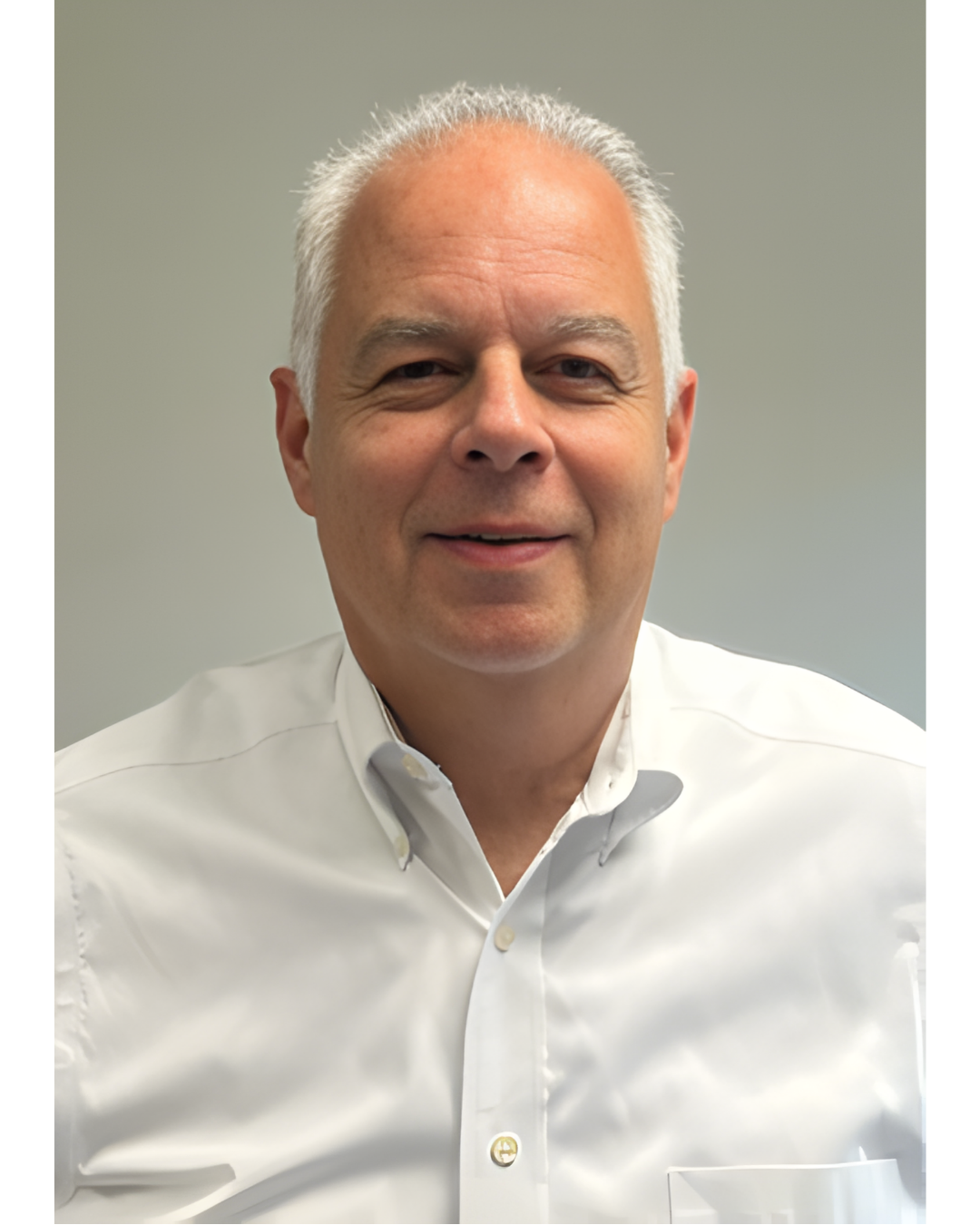 A professional headshot of a person with gray hair, wearing a white button-down shirt, smiling against a plain background.