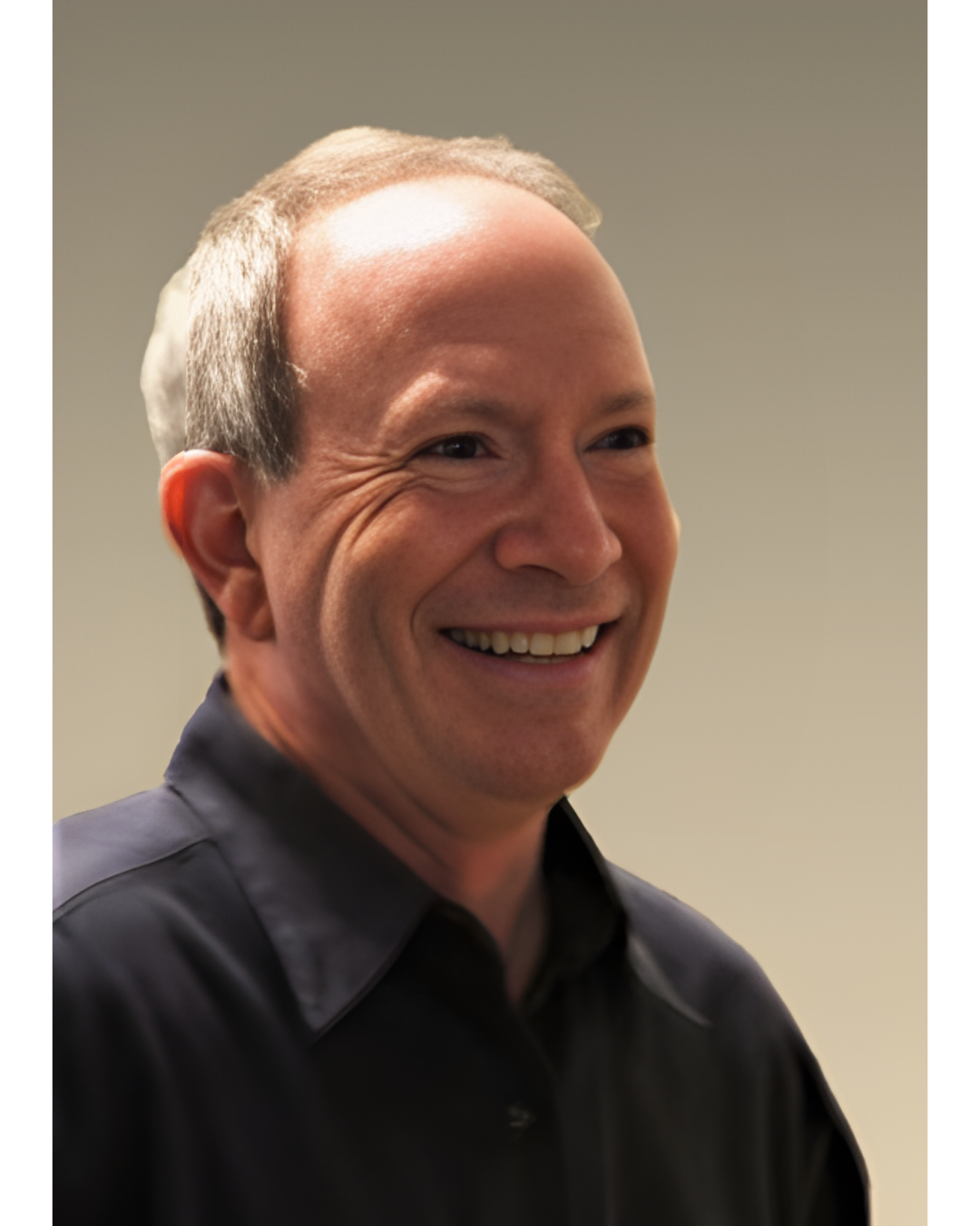 A smiling individual in a dark collared shirt, shown in profile against a plain, light background.