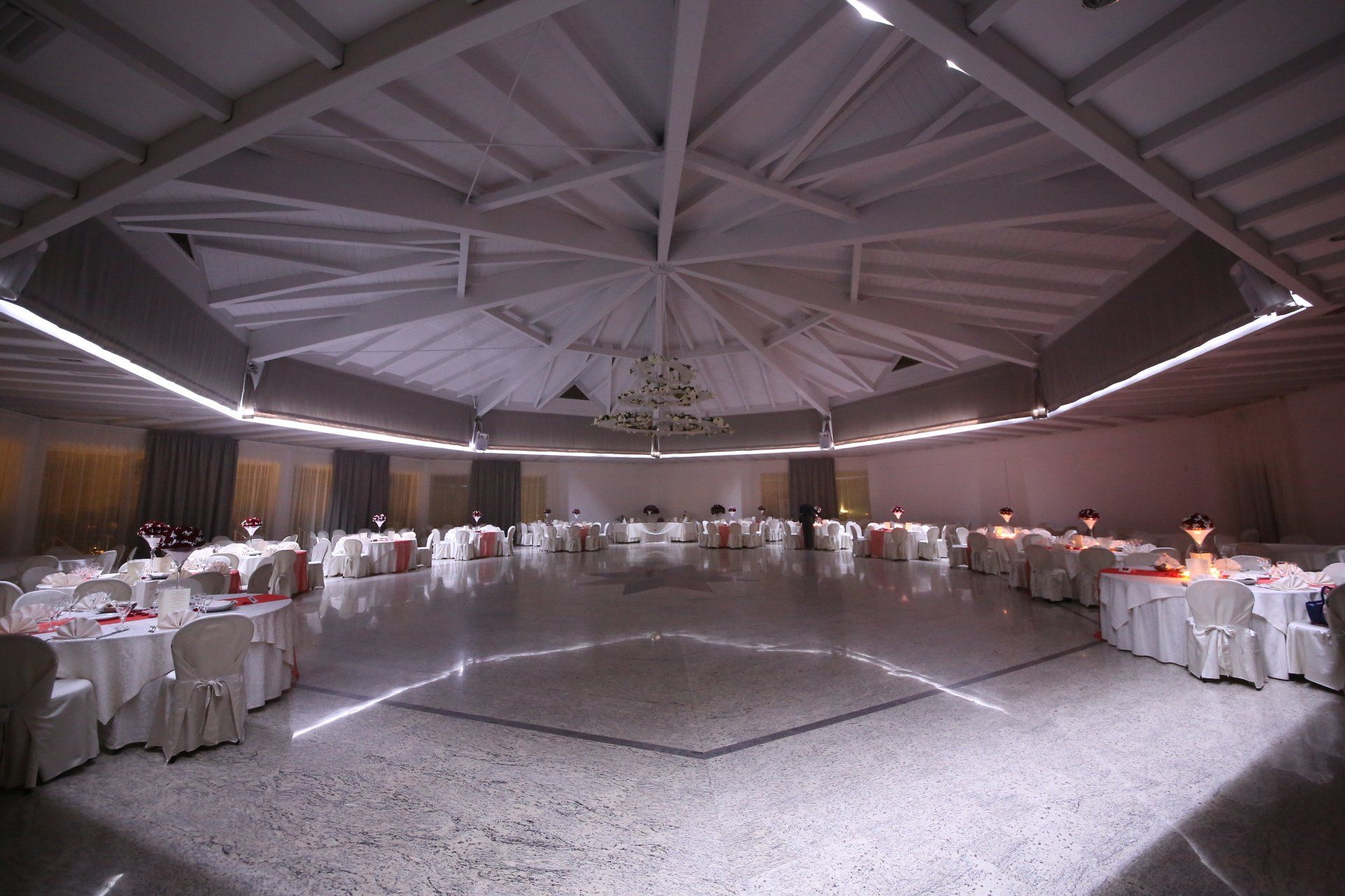 Una grande sala con tavoli e sedie e una pista da ballo