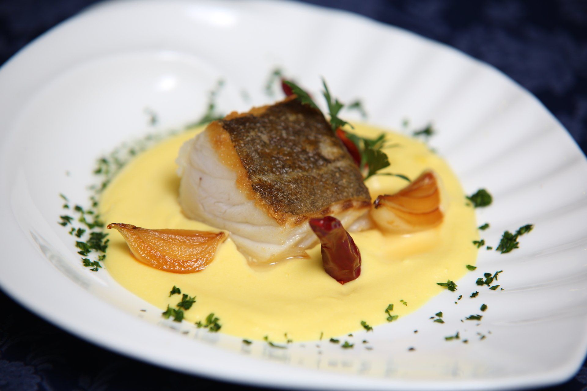 Un piatto bianco con sopra un pezzo di pesce e salsa