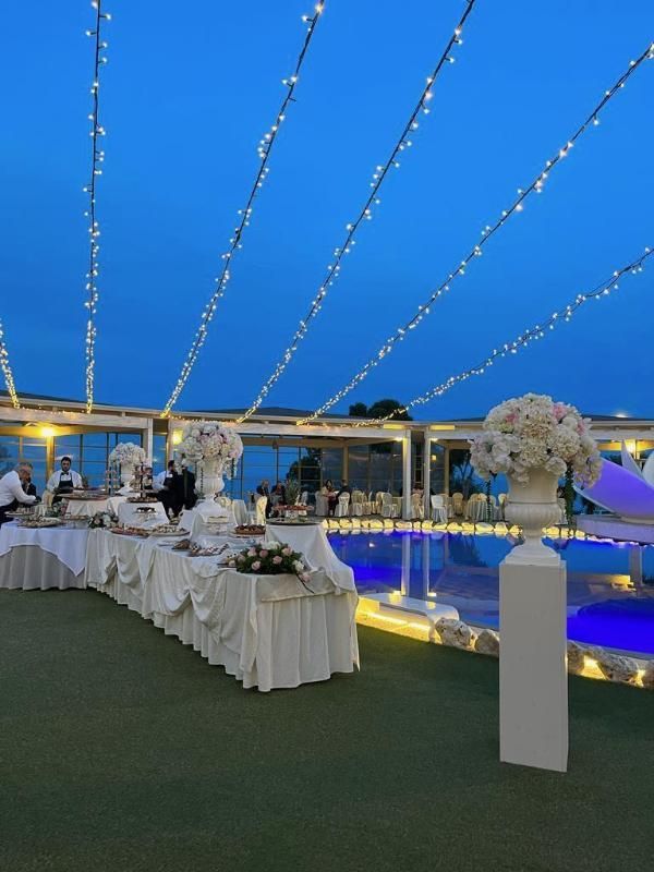 Elegante cena all'aperto illuminata da lucine a bordo piscina, al crepuscolo, con una luce blu intensa.
