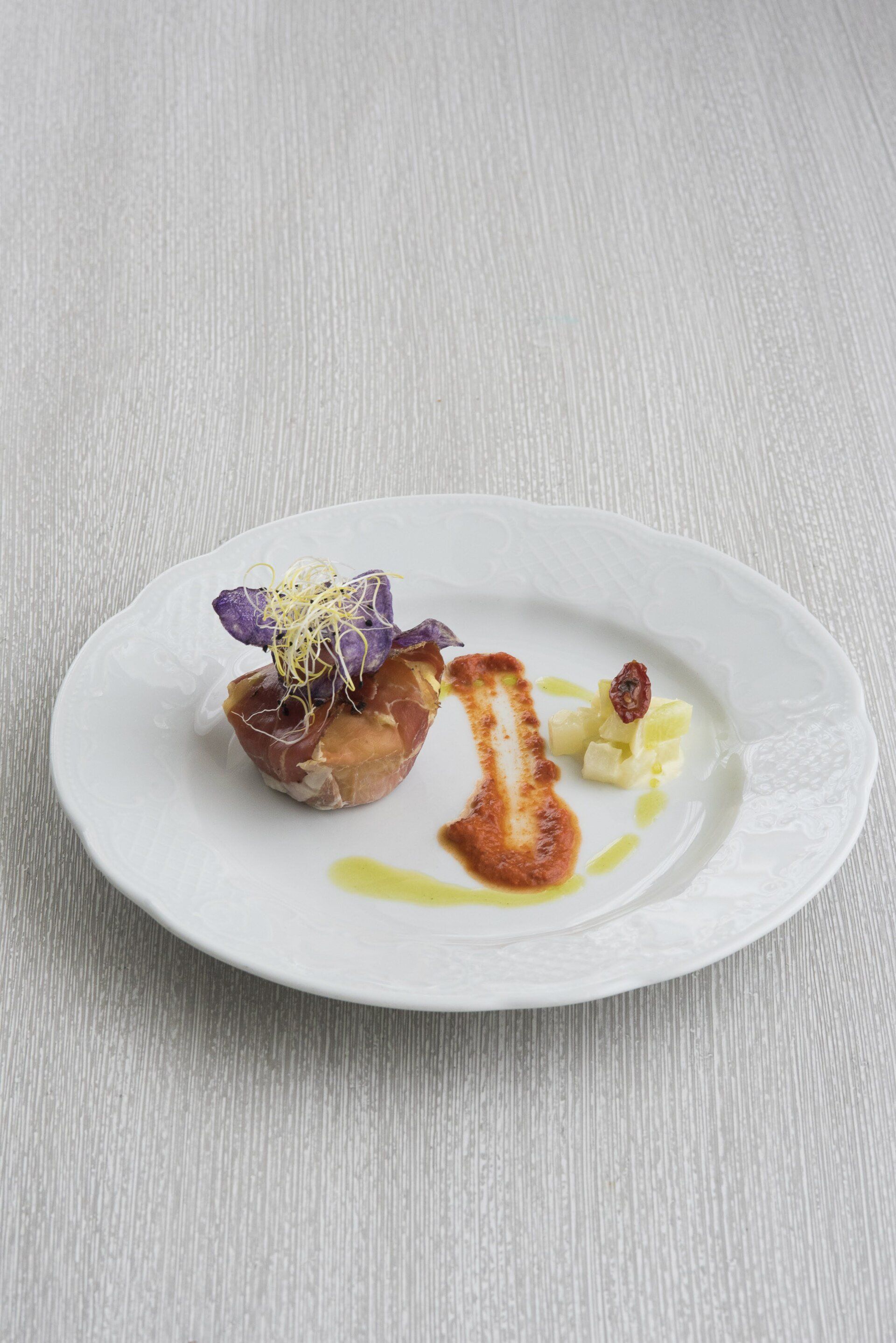 Un piatto bianco sormontato da un pezzo di cibo su un tavolo.