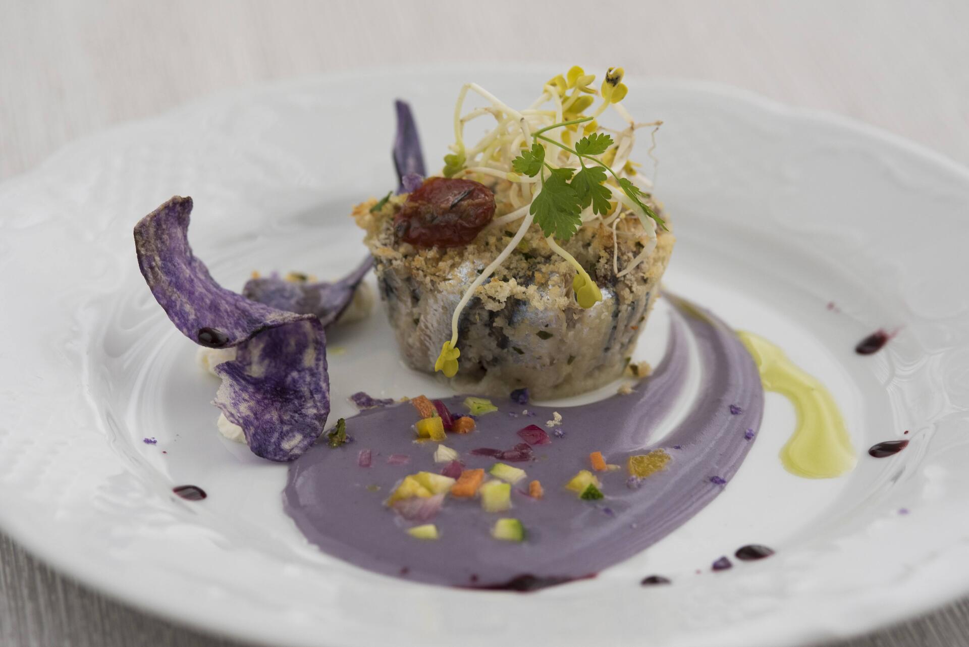 Un piatto bianco condito con una salsa viola e un fiore viola.