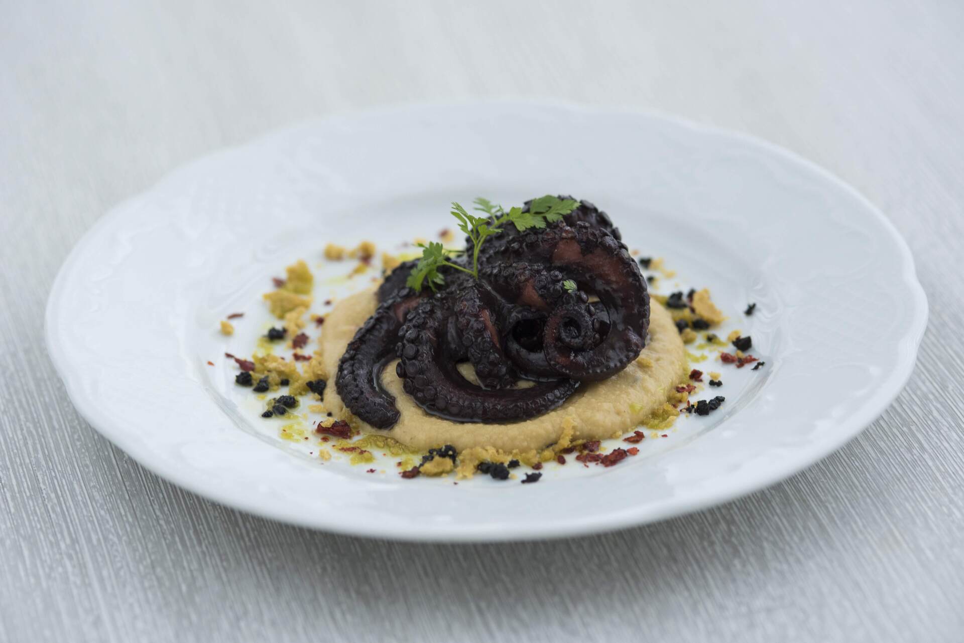 Un piatto di cibo con un polpo sopra un purè di patate su un tavolo.