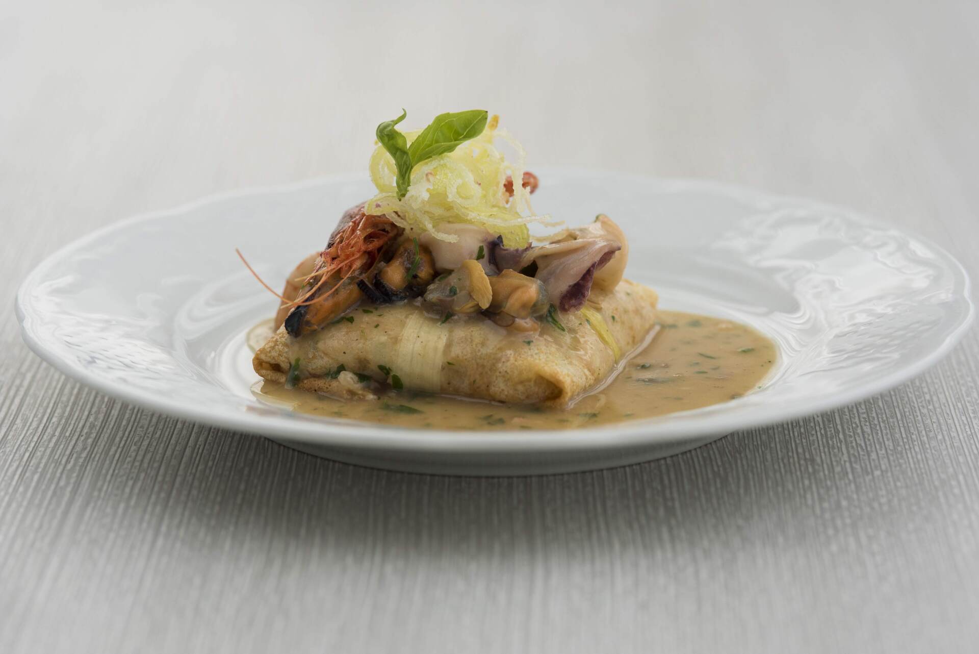 Un piatto bianco con sopra un pezzo di cibo e salsa su un tavolo.