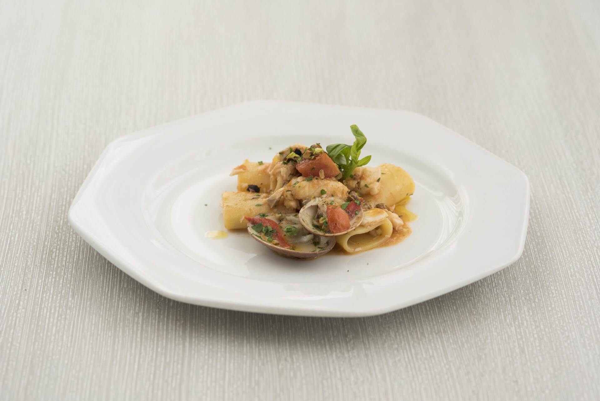 Un piatto bianco con sopra un piatto di pasta su un tavolo.