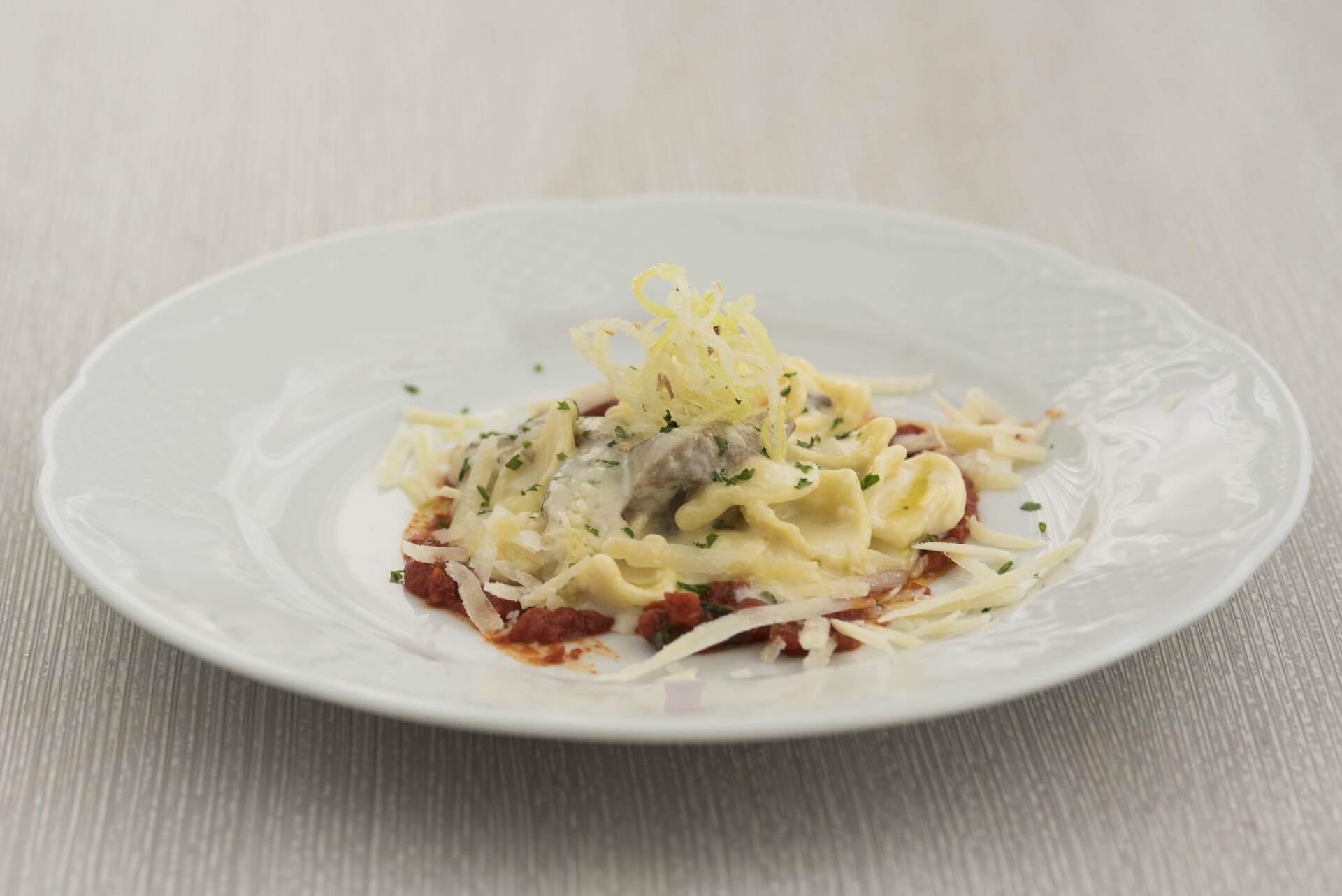 Un piatto bianco con sopra pasta e formaggio su un tavolo.