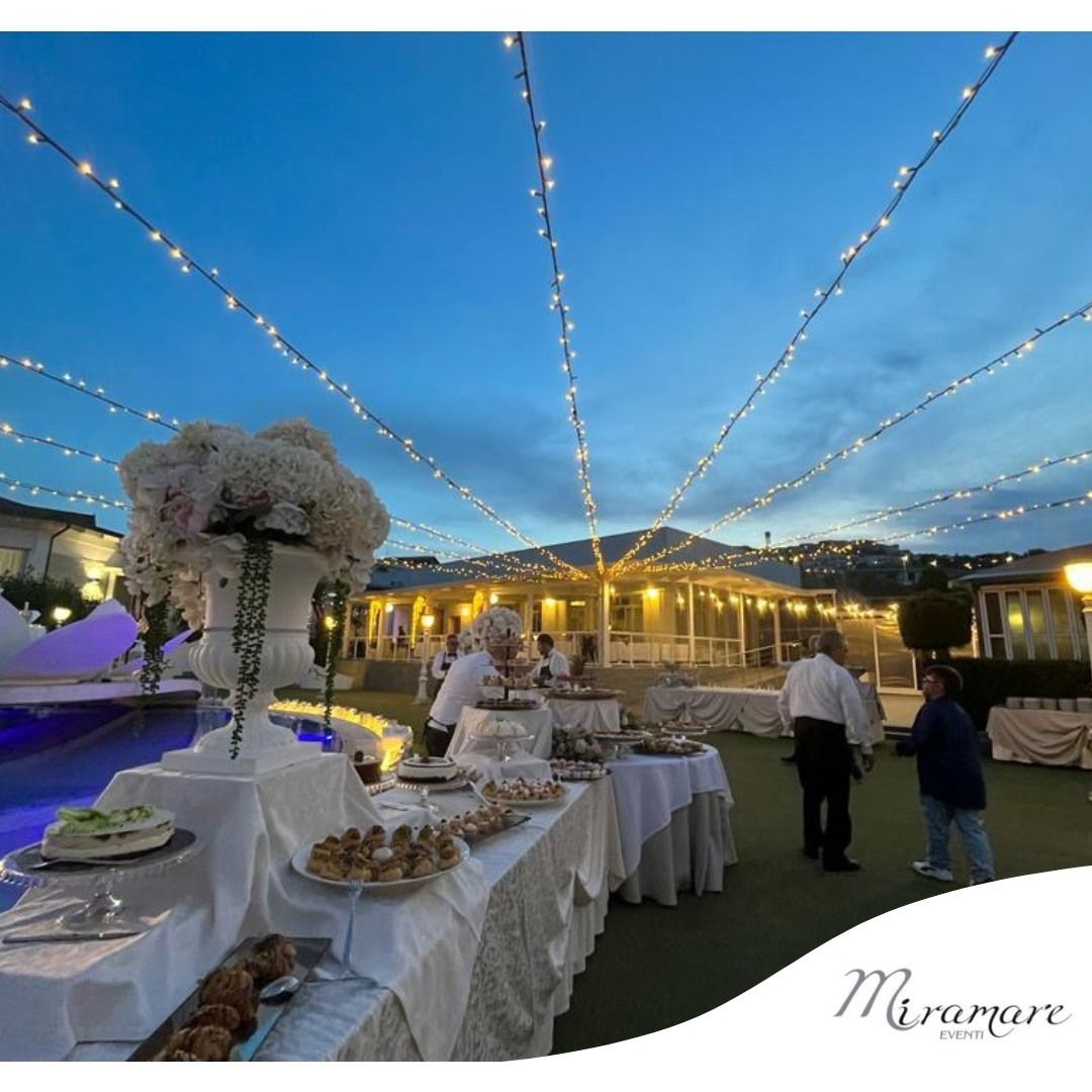 Un gruppo di persone è in piedi attorno a un tavolo con del cibo sopra.