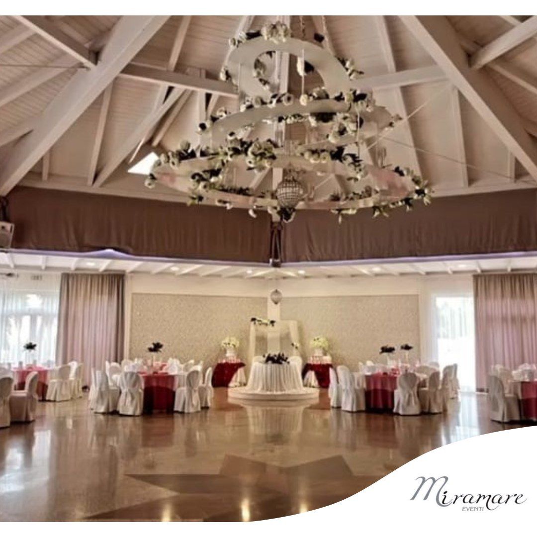 Una grande stanza con tavoli e sedie e un grande lampadario