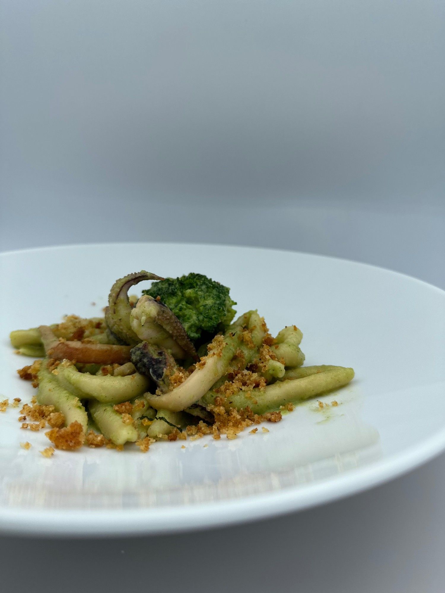 Un piatto bianco con sopra pasta e broccoli su un tavolo.