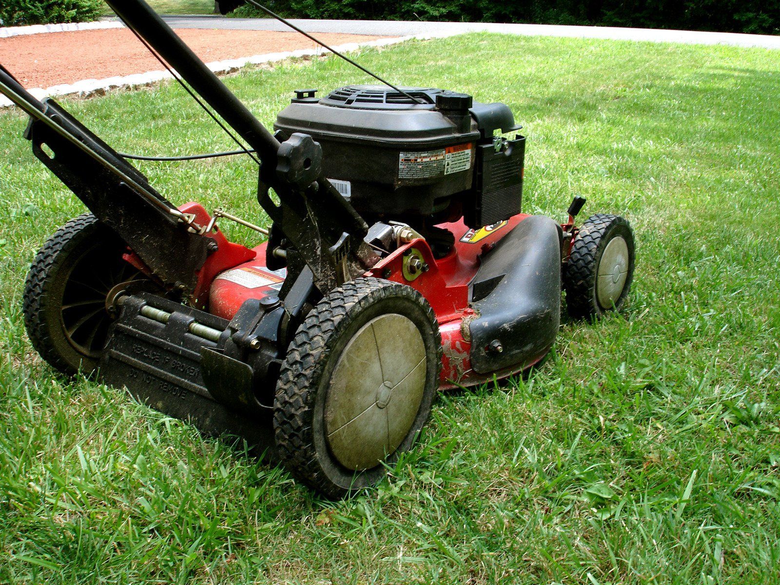Trench dug in a grassy yard, leading to a house with black siding, and an electrical box.