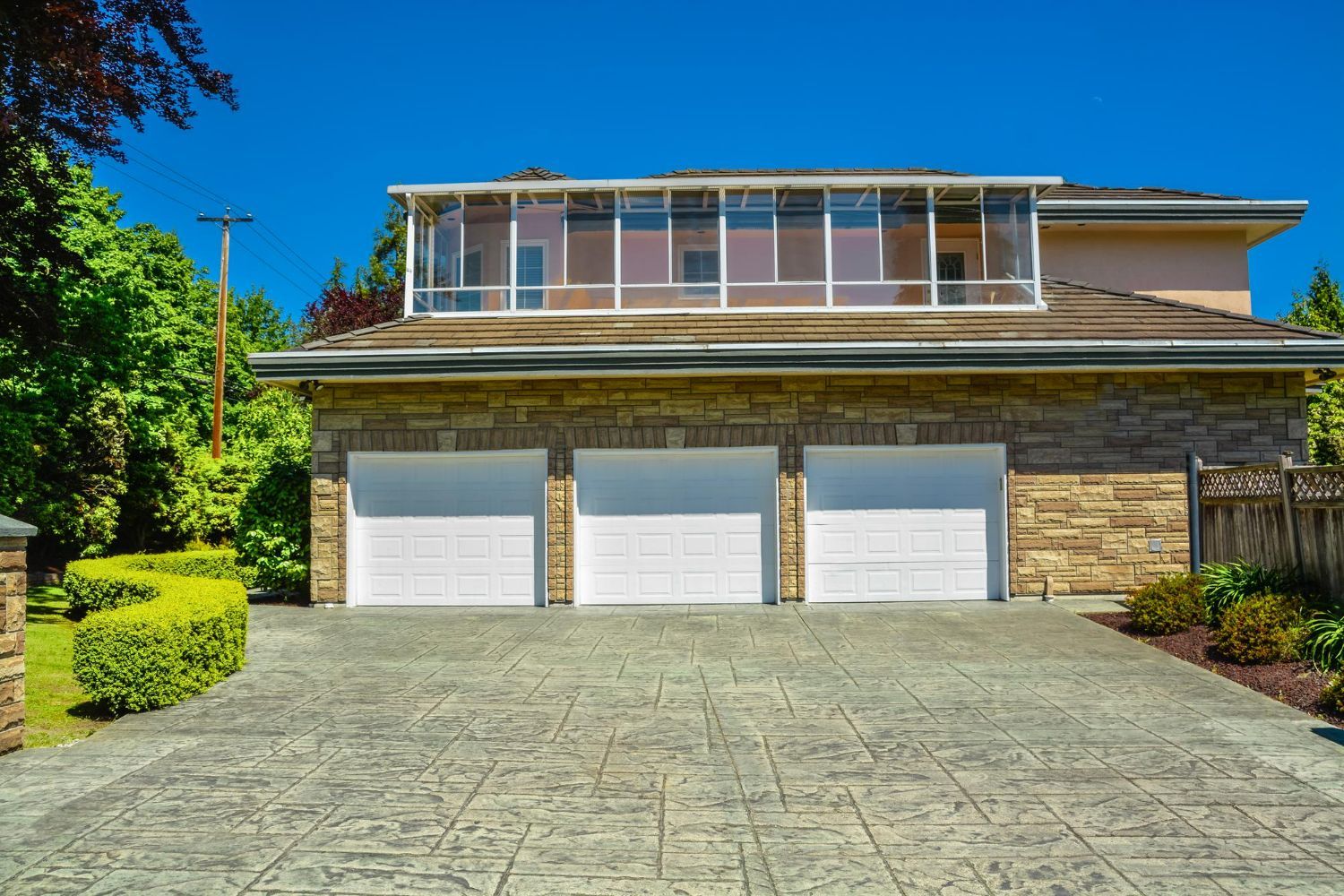 A large house with three garage doors and a large screened in porch.