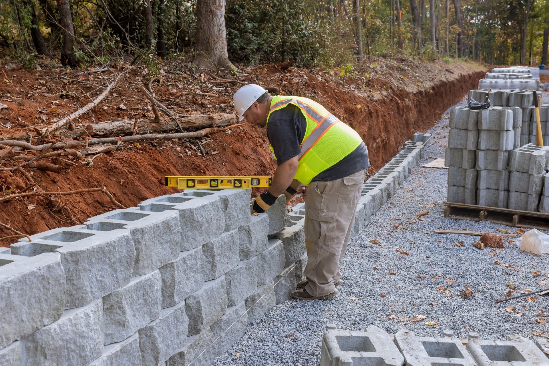 A construction worker is measuring a brick wall with a level.