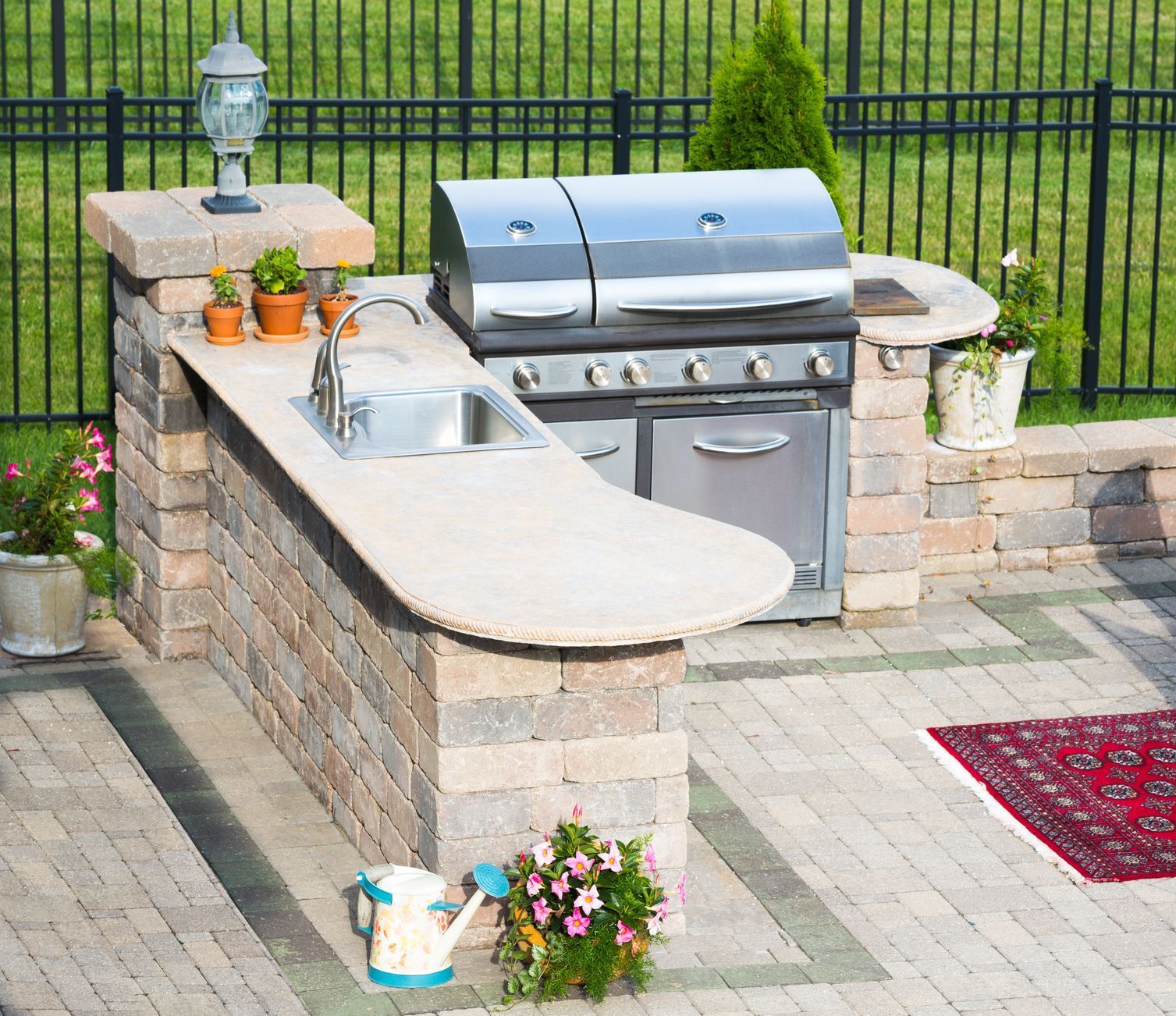 A patio with a grill , sink , table and chairs.