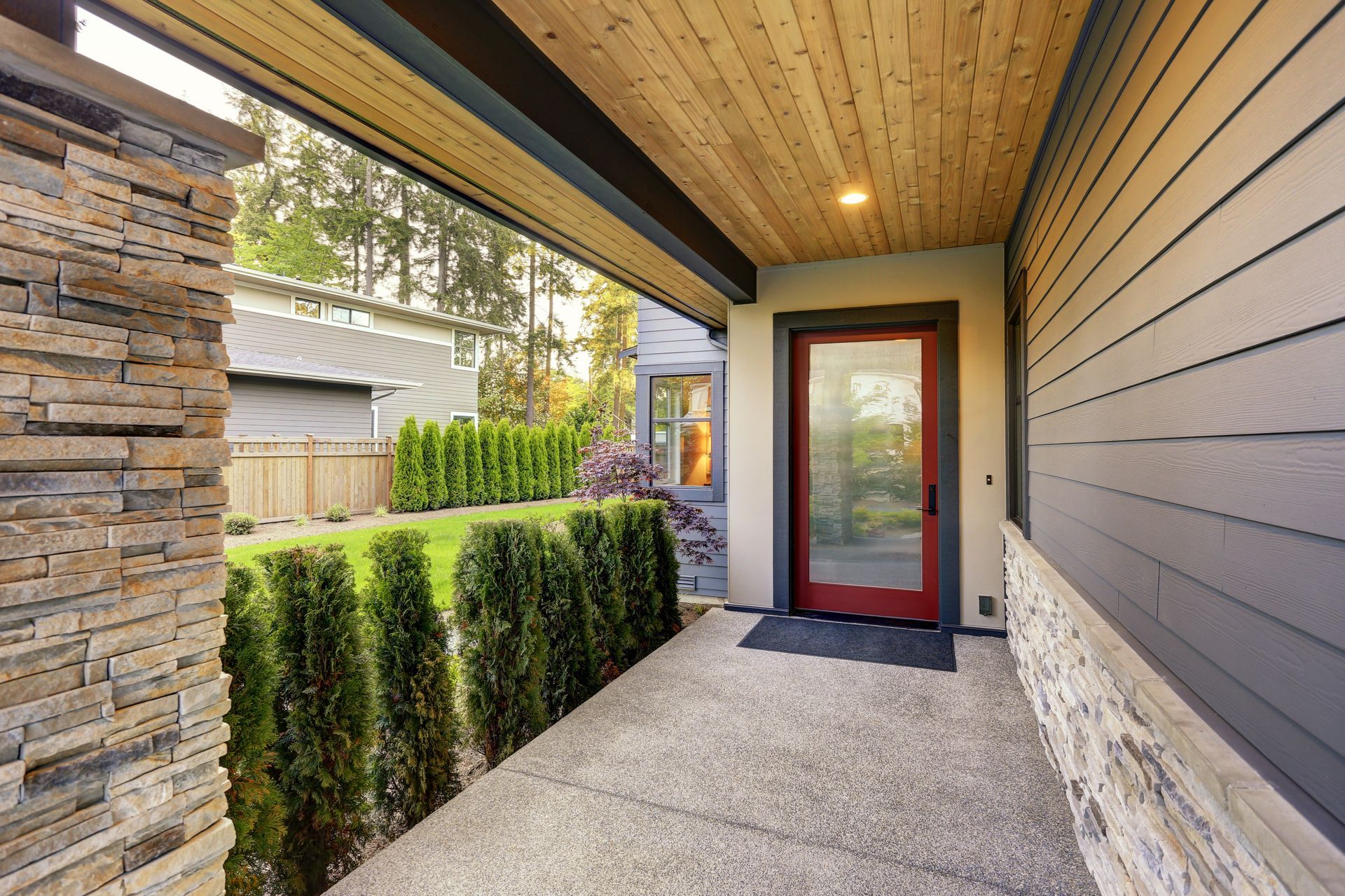 A porch with a red door and a wooden ceiling