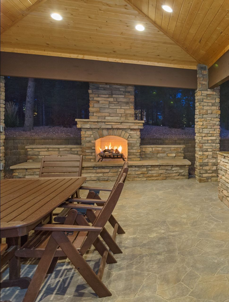 A patio with a table and chairs and a fireplace