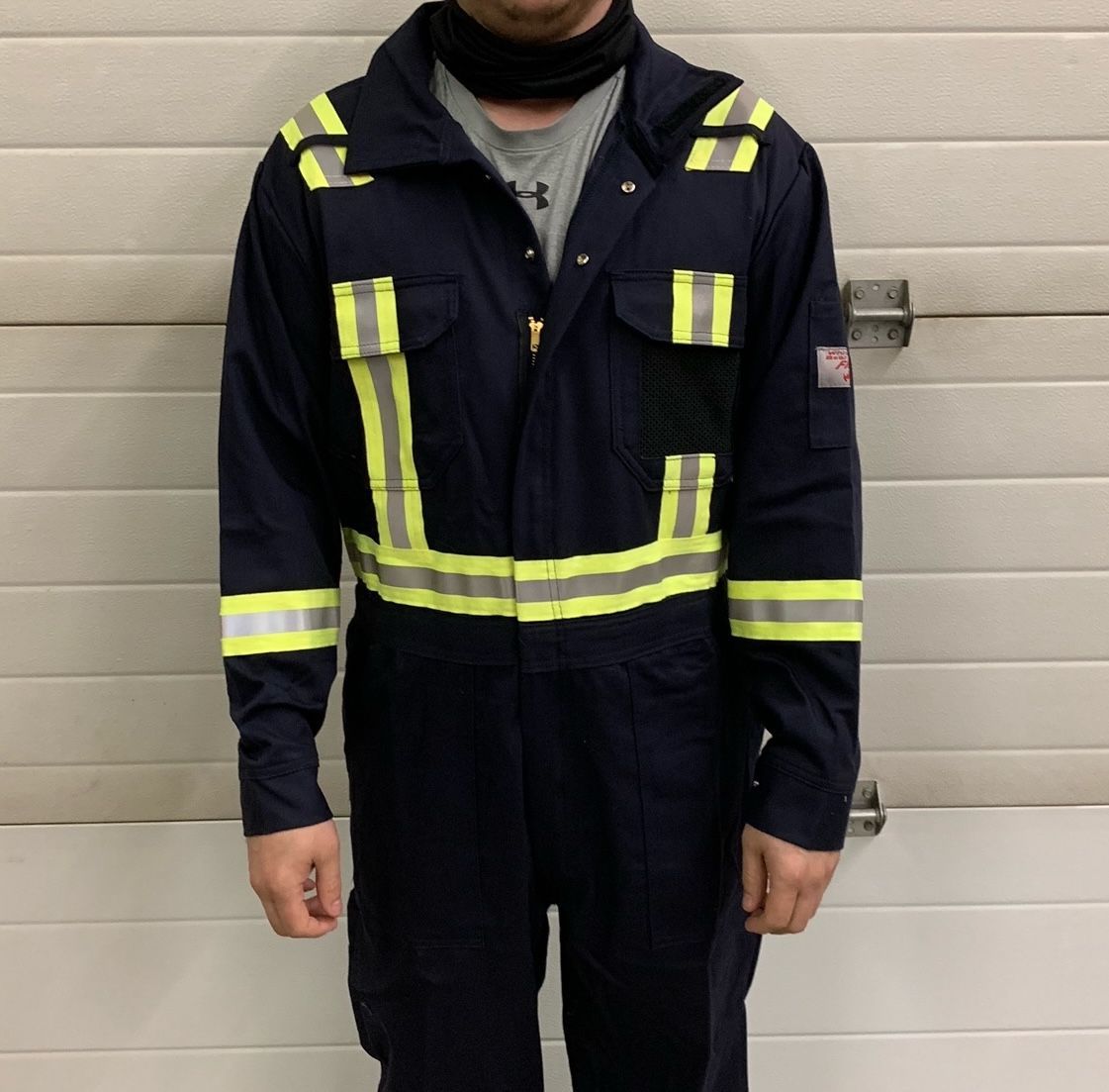 Close-up of a gray firefighter jacket sleeve with reflective stripes and patches.