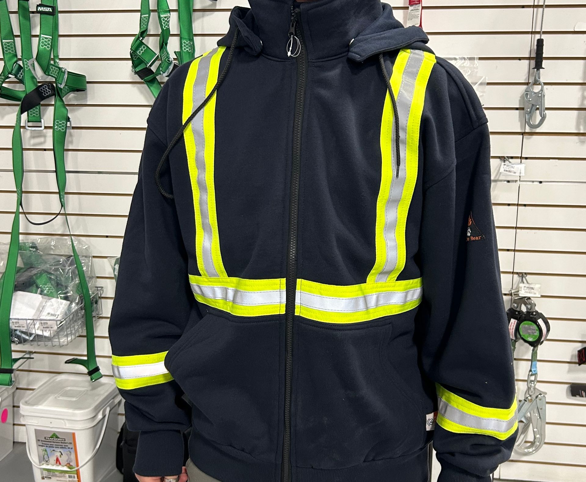 Person wearing a navy blue hooded sweatshirt with reflective yellow stripes.