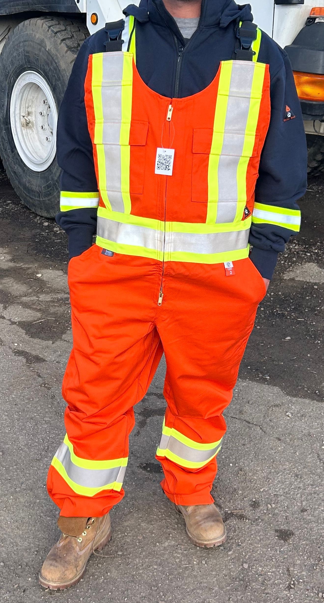 Person in orange jumpsuit with reflective stripes, black jacket, and work boots.