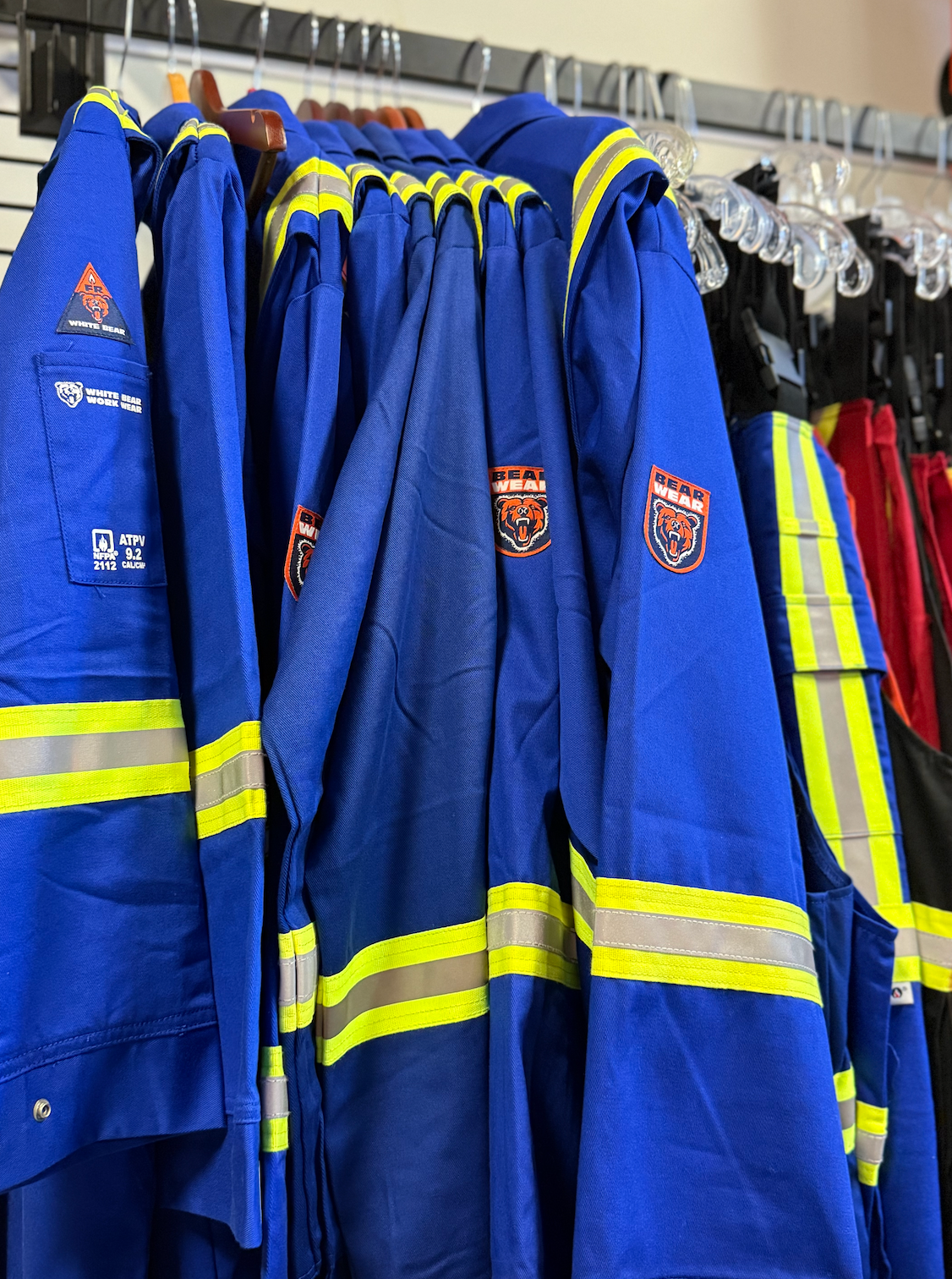 Blue work coveralls with reflective stripes hanging on a rack.