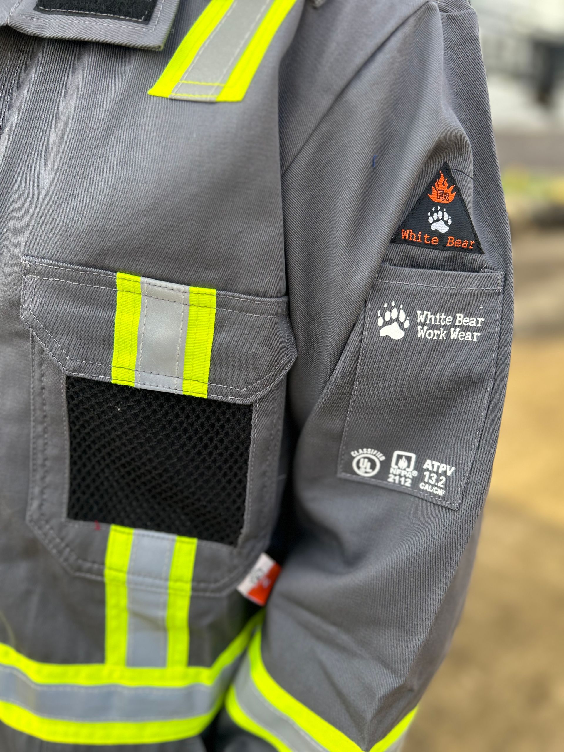 Close-up of a gray firefighter jacket sleeve with reflective stripes and patches.