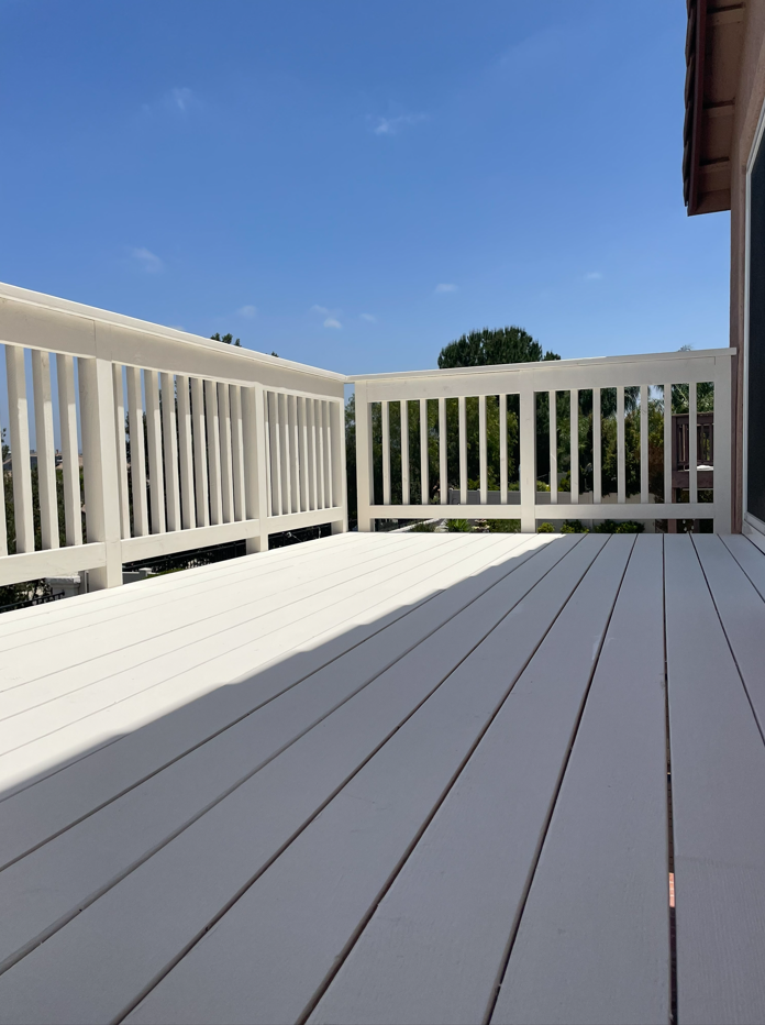 White wooden deck with matching railing against a bright blue sky.