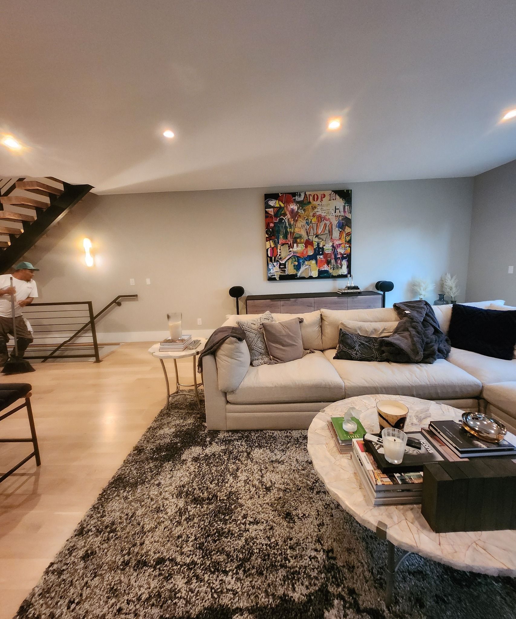 Living room with large sectional sofa, abstract art, and shaggy rug.