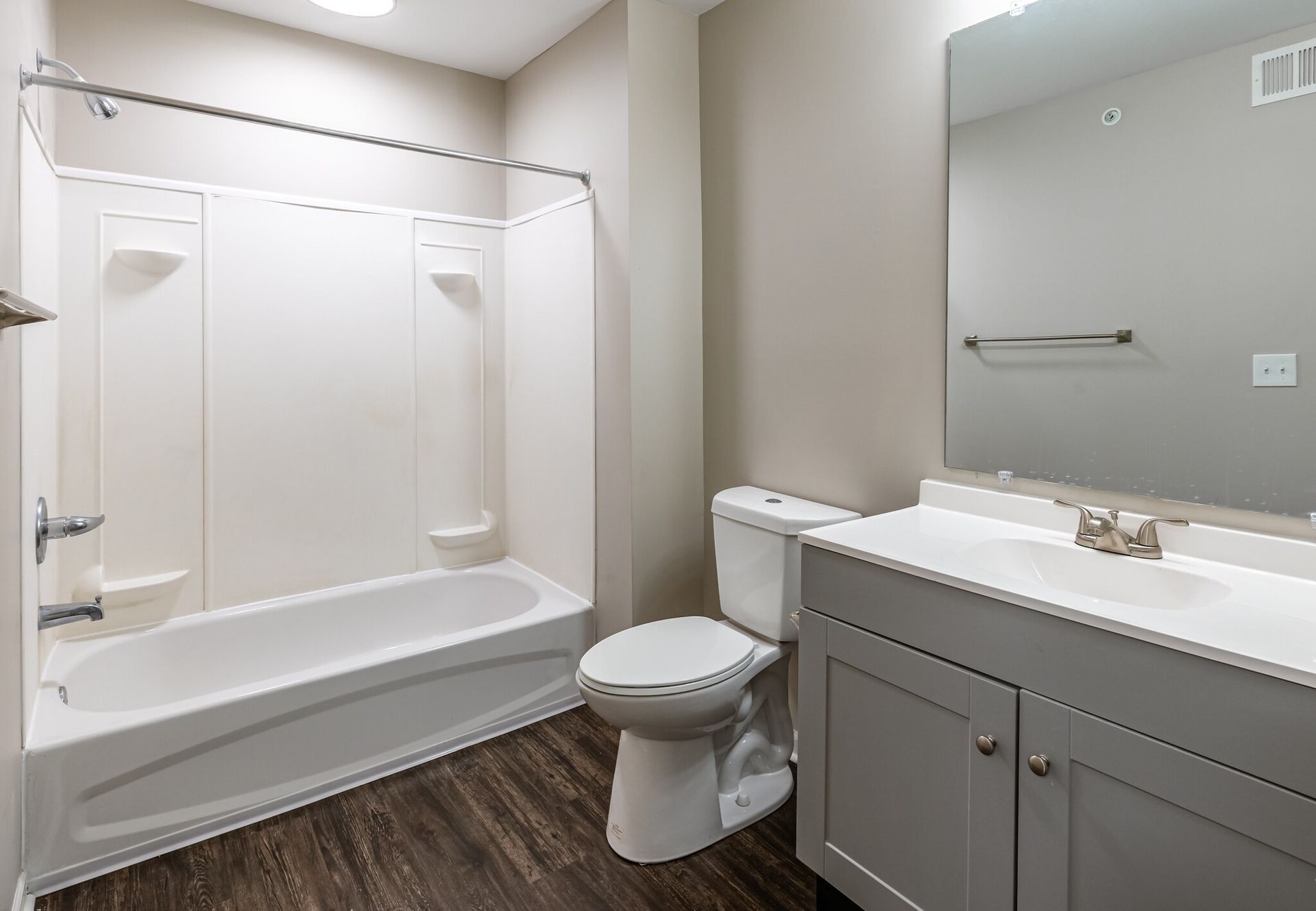 A bathroom with a toilet , sink , bathtub and mirror.