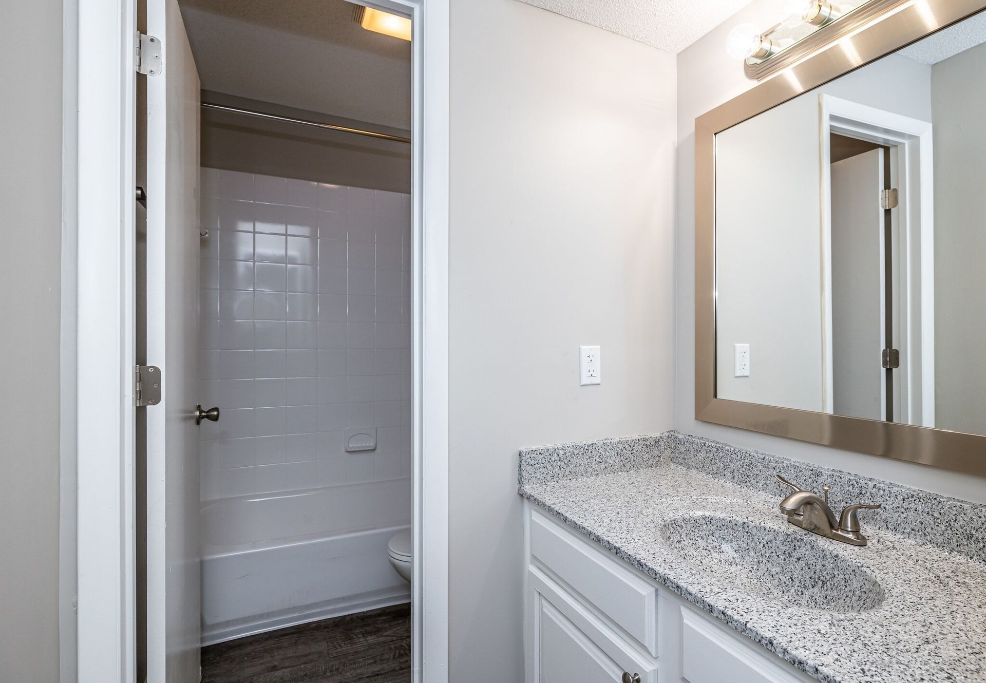 A bathroom with a sink , mirror and bathtub.