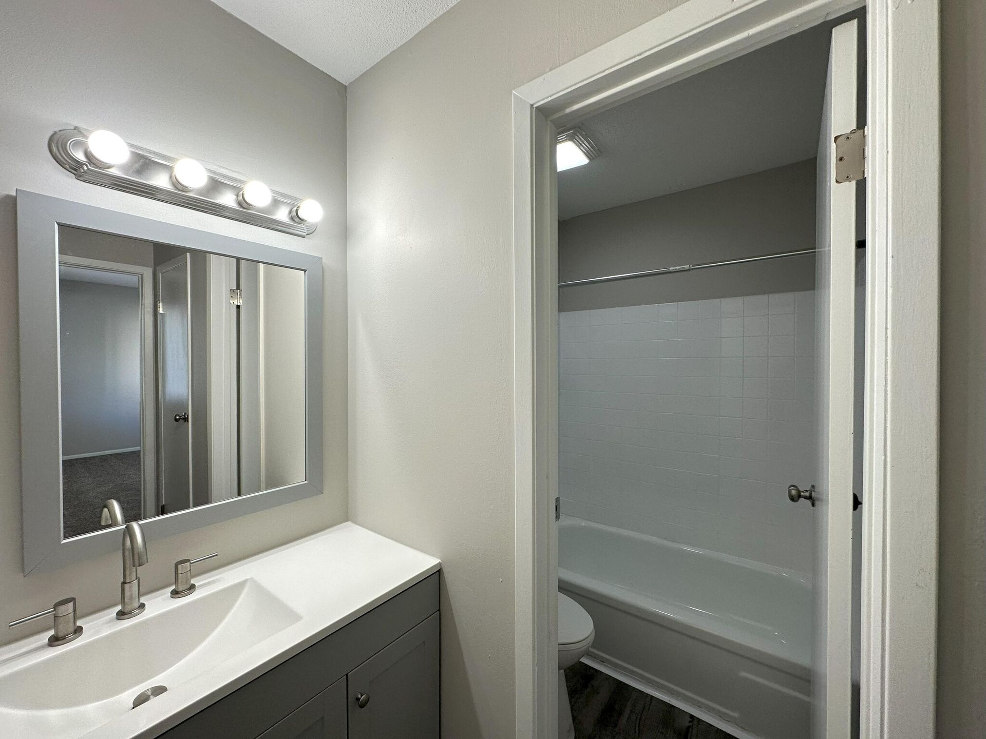 A bathroom with a sink , mirror and tub.