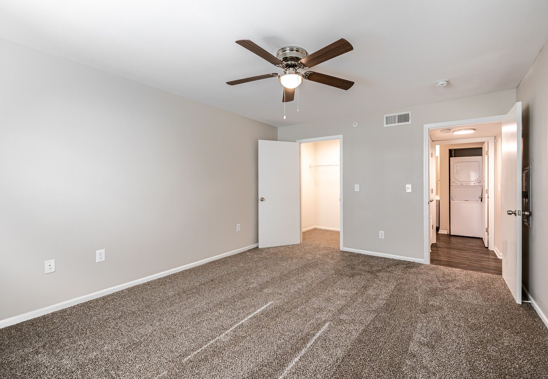 An empty room with a ceiling fan and a carpeted floor.