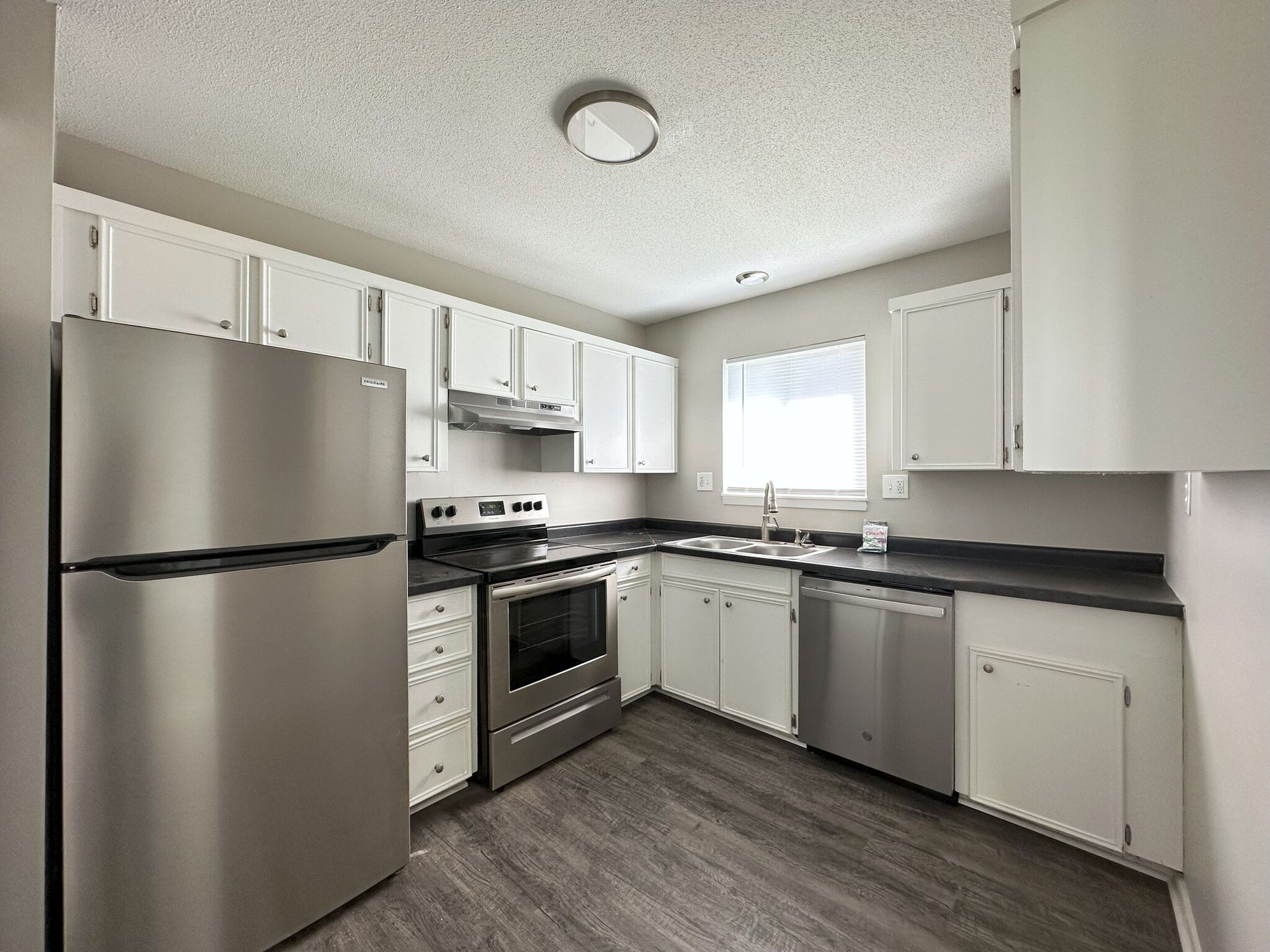 A kitchen with stainless steel appliances and white cabinets.