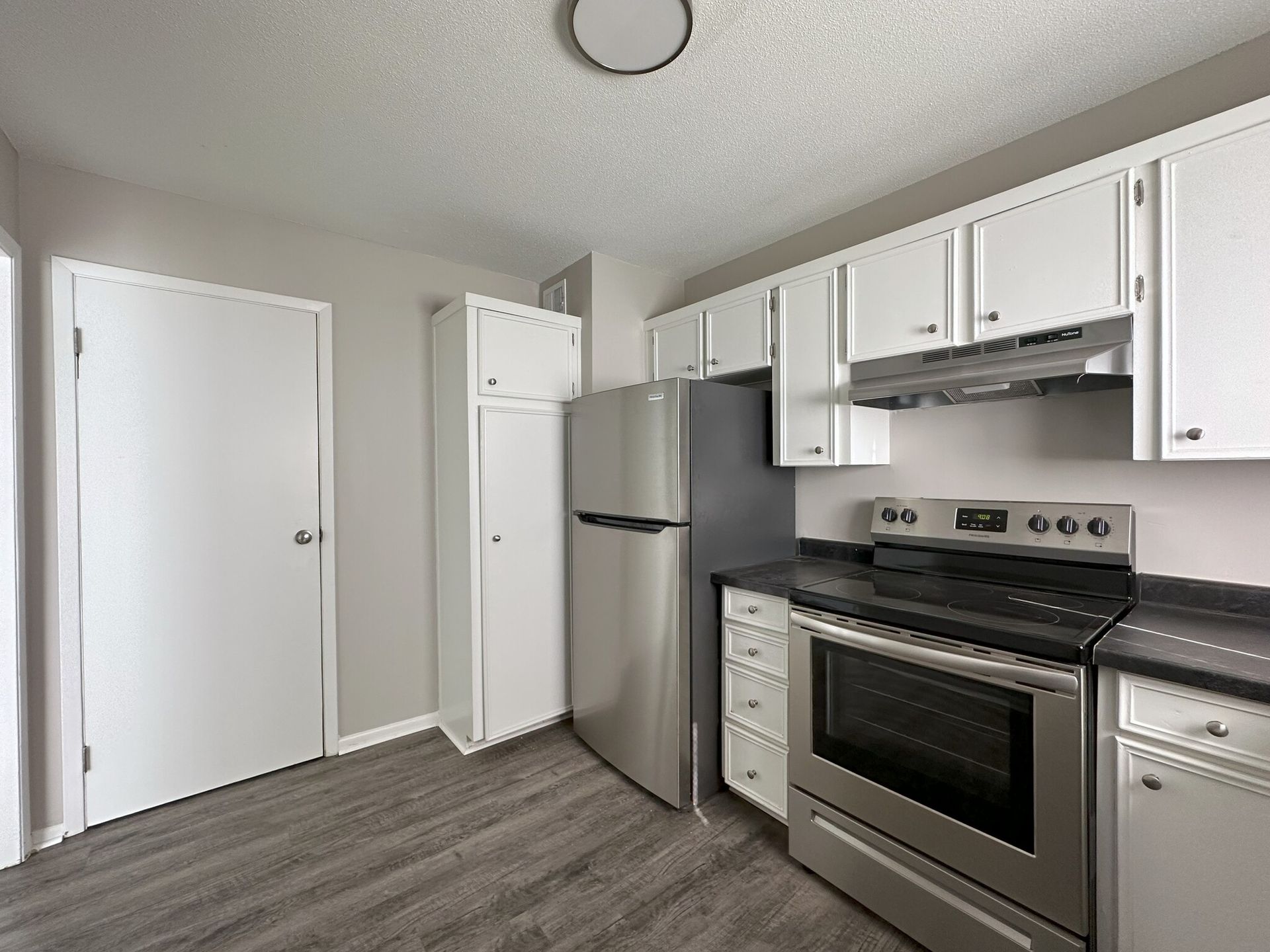 A kitchen with stainless steel appliances and white cabinets.