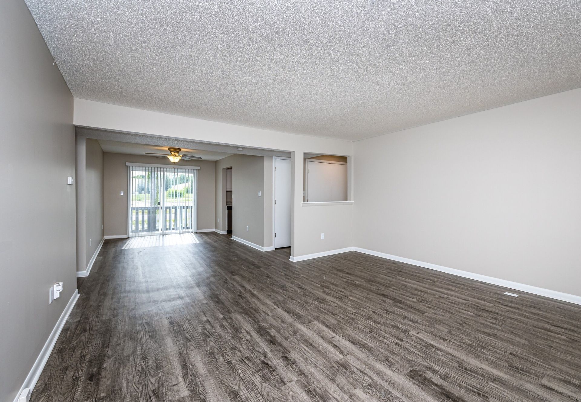 An empty living room with hardwood floors and a balcony.