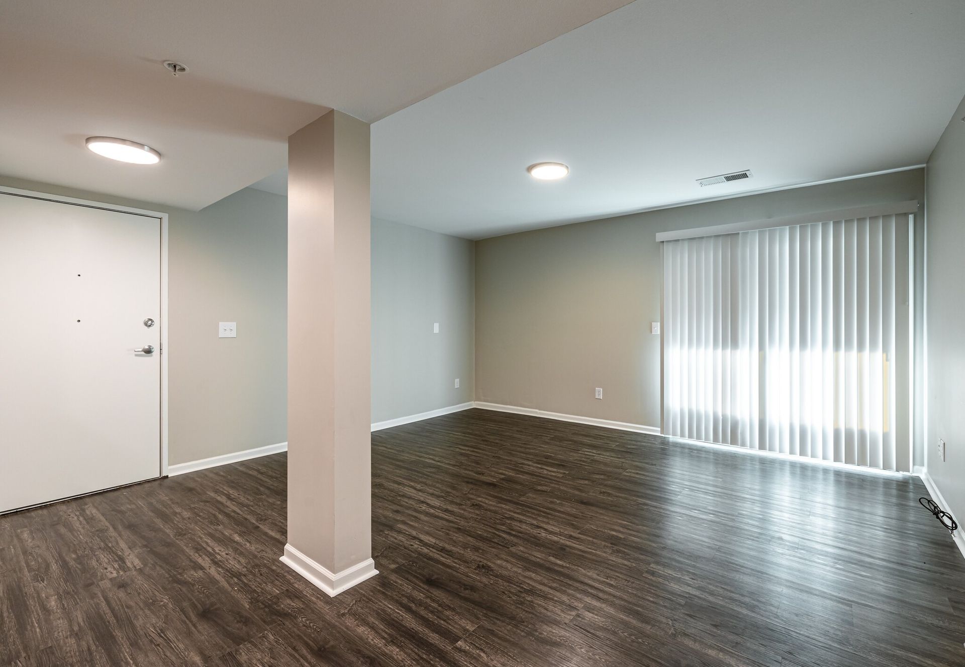 An empty living room with hardwood floors and sliding glass doors.