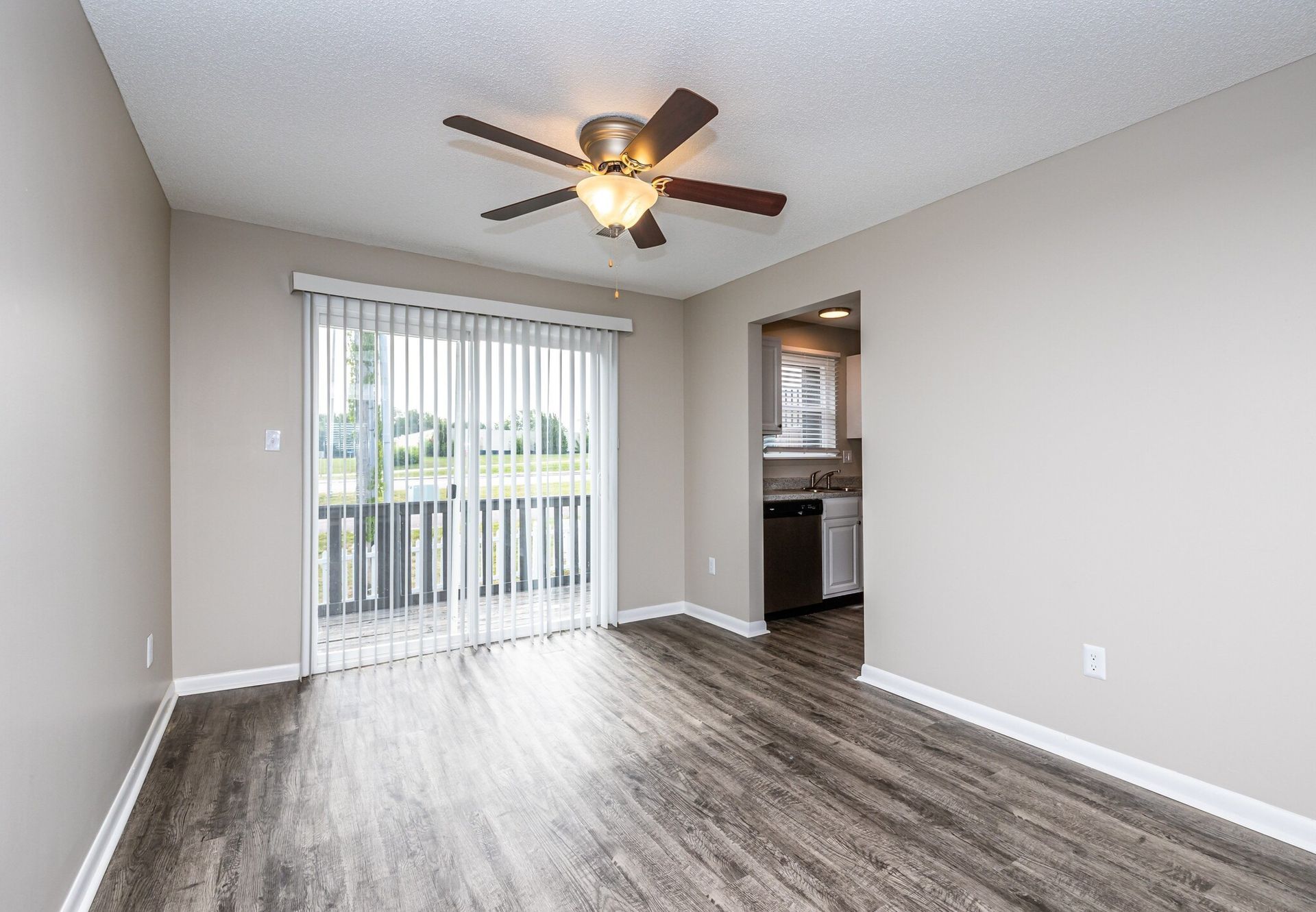 An empty living room with hardwood floors and a ceiling fan.