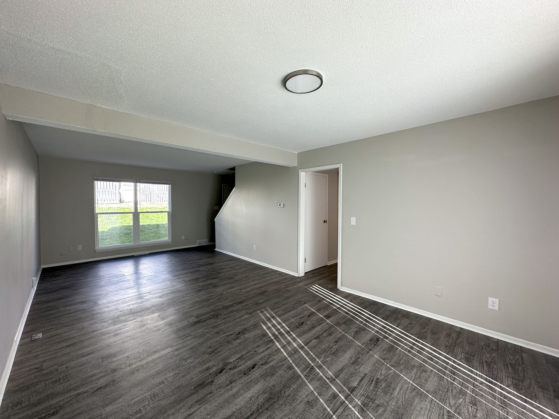 An empty living room with hardwood floors and gray walls.
