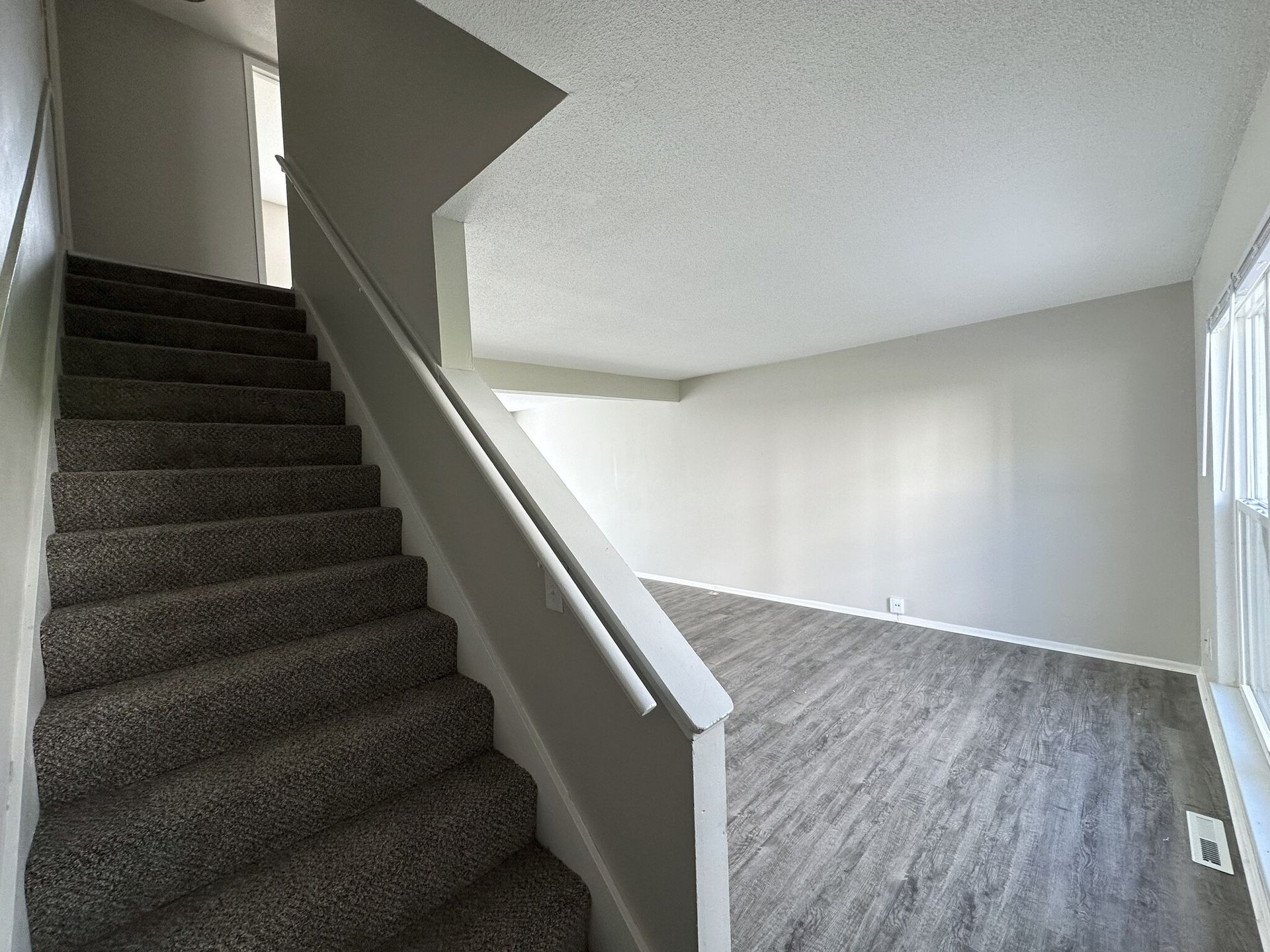 An empty living room with stairs leading up to the second floor
