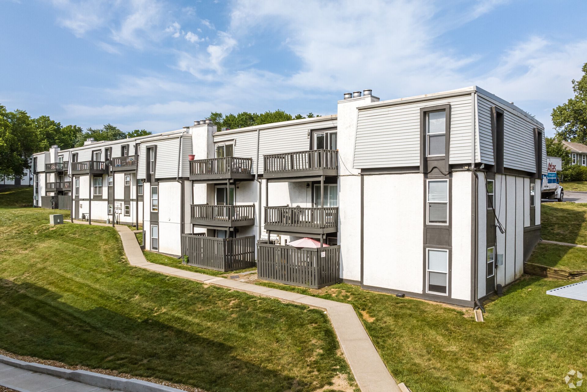 A large white apartment building with a walkway leading to it.