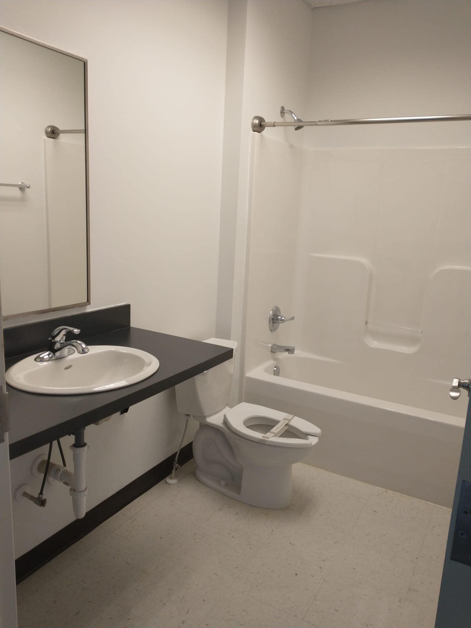 Bathroom with white walls, a sink, toilet, and bathtub/shower.