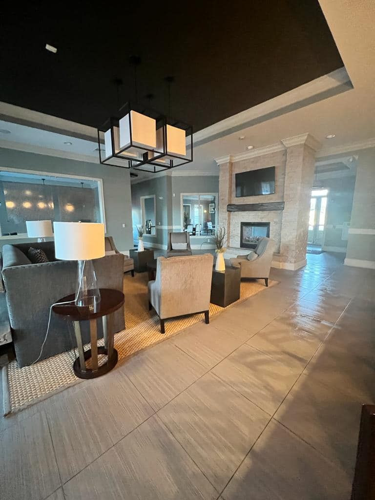 Lounge area with seating, fireplace, and modern chandelier under a black ceiling.