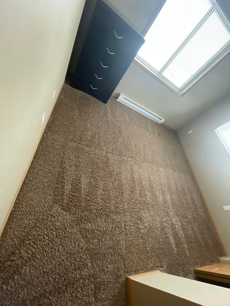 Room with brown carpet, skylight, black cabinet, and an air conditioning unit.