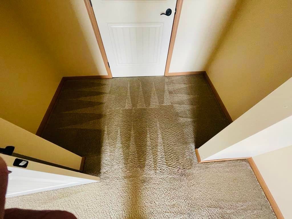 Looking down a hallway with beige carpet, door at the end, and tan walls.