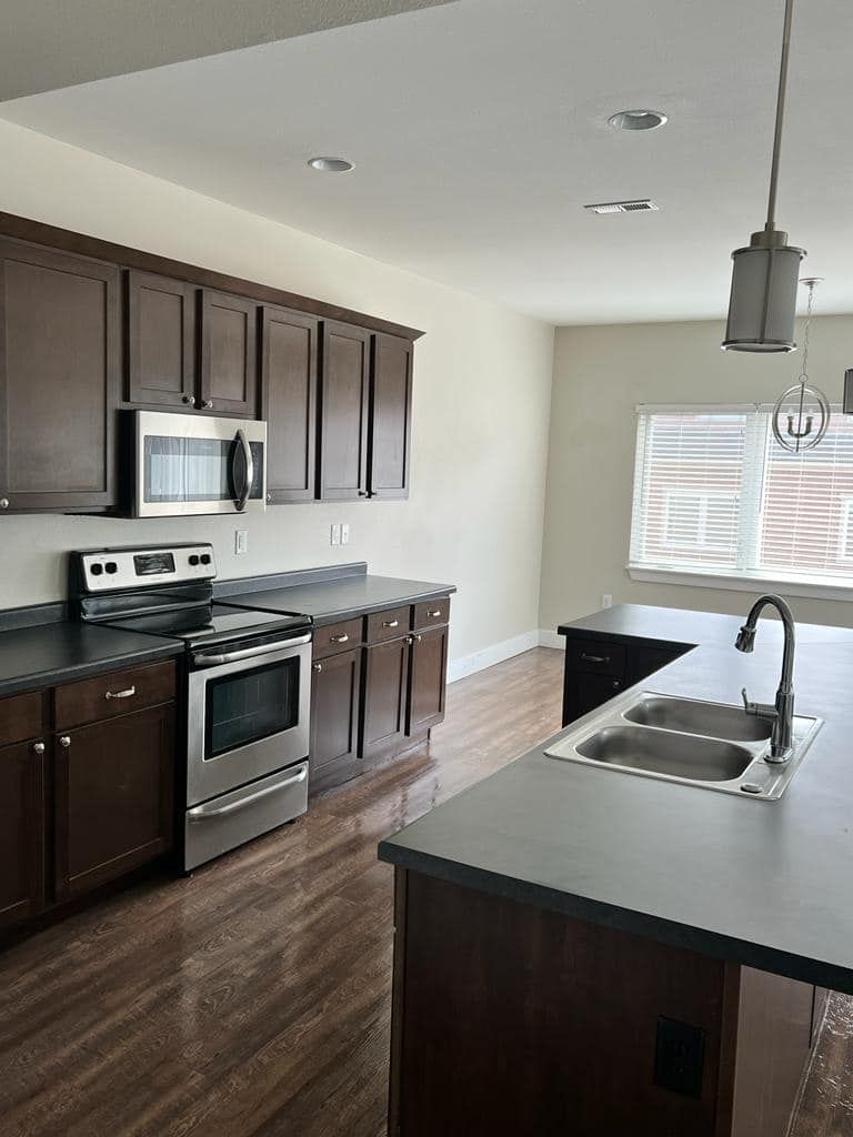 Dark-wood kitchen with stainless steel appliances, an island, and a window.